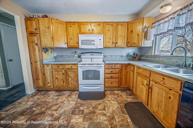 kitchen with white appliances, stone finish flooring, light countertops, and a sink