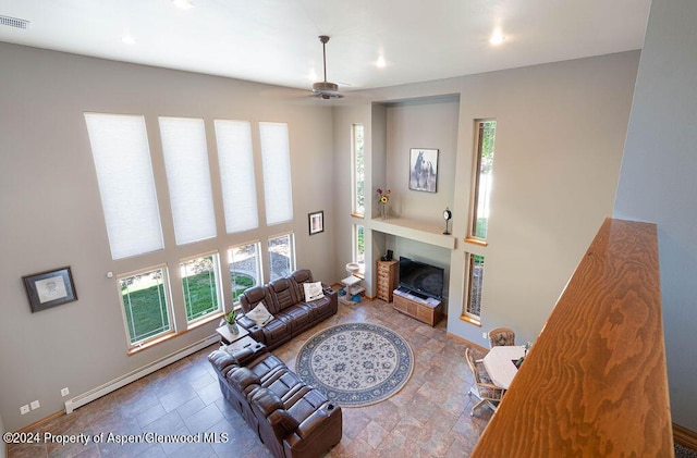 living area with visible vents, a fireplace, baseboards, baseboard heating, and a towering ceiling