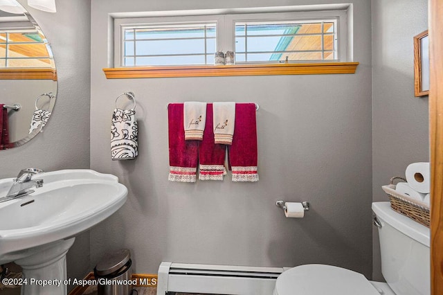 half bath featuring a baseboard heating unit, toilet, and a sink