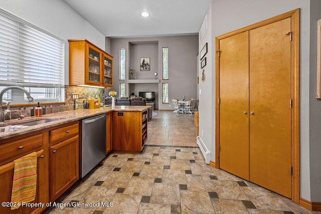 kitchen featuring a baseboard radiator, a sink, stainless steel dishwasher, brown cabinets, and backsplash