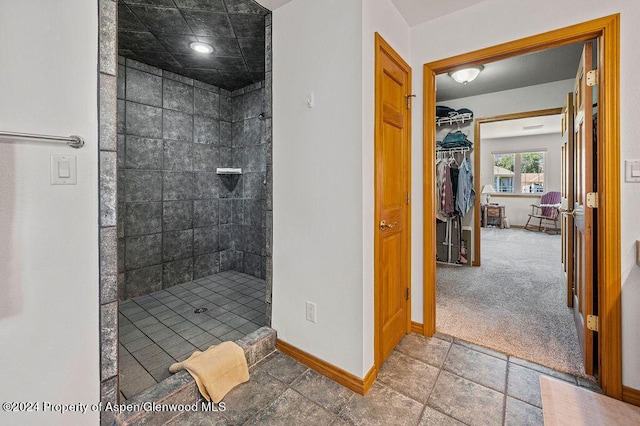 full bath with a spacious closet, baseboards, and a stall shower