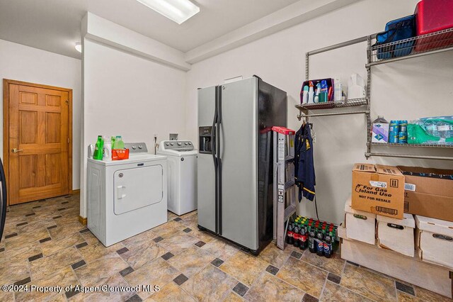 washroom with stone finish flooring, washing machine and dryer, and laundry area