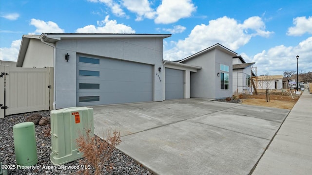 view of property exterior featuring stucco siding, an attached garage, a gate, fence, and driveway