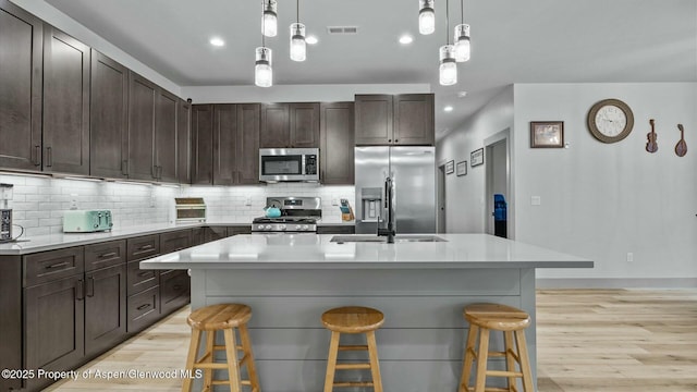 kitchen with visible vents, appliances with stainless steel finishes, a breakfast bar, and tasteful backsplash