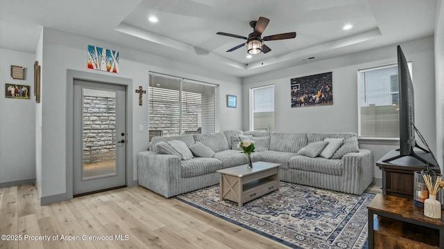 living area featuring light wood-type flooring, a raised ceiling, and recessed lighting