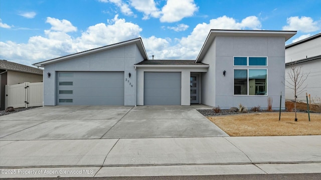 view of front of home with a garage, fence, driveway, a gate, and stucco siding