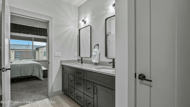 ensuite bathroom featuring double vanity, wood finished floors, ensuite bath, and a sink