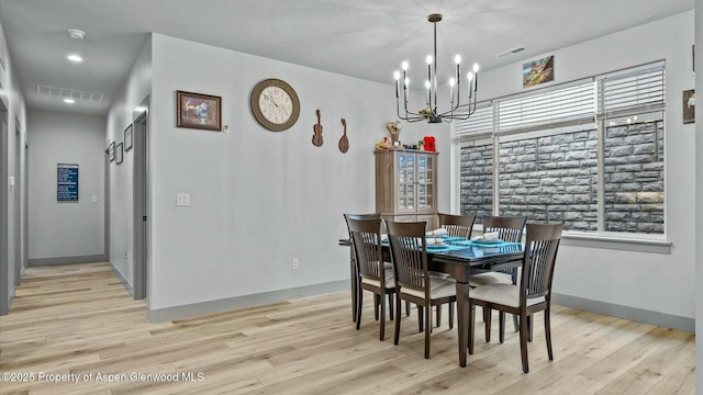 dining area featuring light wood-style flooring, visible vents, and a chandelier