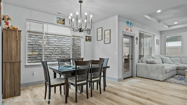 dining area featuring a wealth of natural light, light wood-type flooring, visible vents, and an inviting chandelier