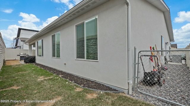 view of side of home featuring central AC unit, fence, a lawn, and stucco siding