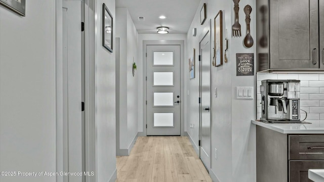 doorway featuring light wood finished floors, visible vents, and baseboards