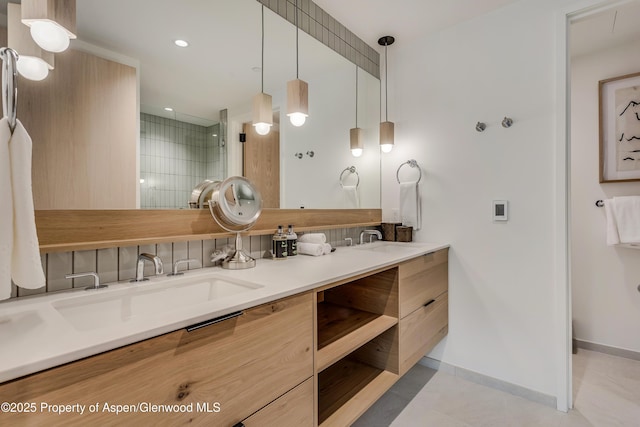 bathroom with baseboards, double vanity, recessed lighting, tiled shower, and a sink