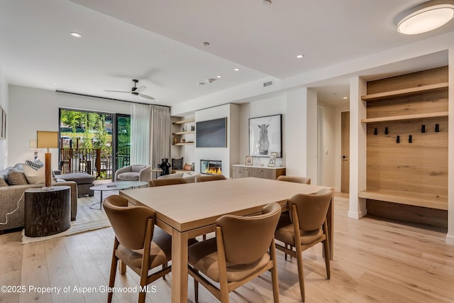 dining space featuring a ceiling fan, visible vents, recessed lighting, light wood-style floors, and a glass covered fireplace