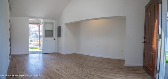 entryway with vaulted ceiling, hardwood / wood-style floors, and electric panel