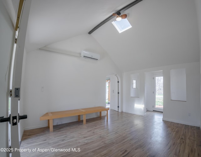 interior space with beam ceiling, a skylight, high vaulted ceiling, a wall mounted air conditioner, and wood-type flooring