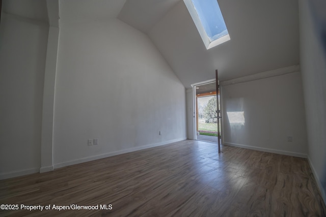 interior space with vaulted ceiling with skylight and dark hardwood / wood-style flooring