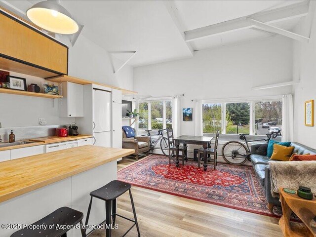 412 Mill St # B9, Aspen, CO 81611 - kitchen with wooden counters, a high ceiling, light wood-style floors, open floor plan, and white cabinets