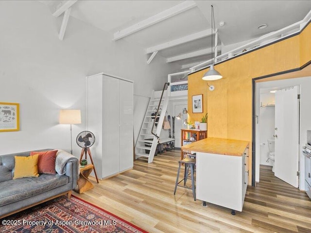 412 Mill St # B9, Aspen, CO 81611 - kitchen featuring light wood-style floors, beam ceiling, hanging light fixtures, a kitchen bar, and a towering ceiling