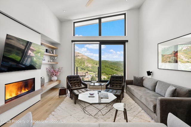 119 Wood Rd Unit 604, Snowmass Village, CO 81615 - living area with a high ceiling, a glass covered fireplace, and light wood-style floors