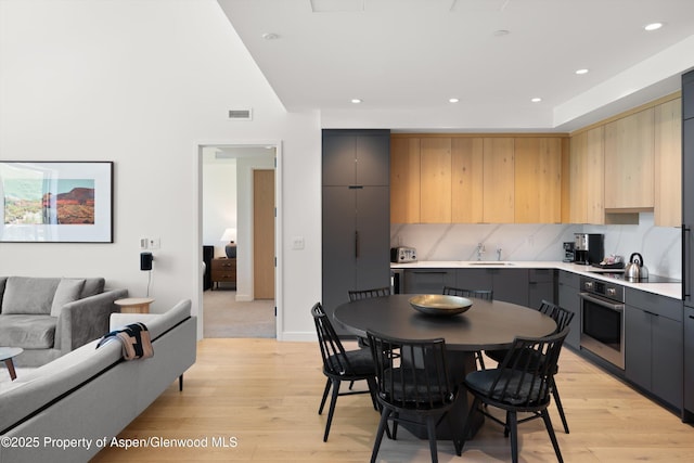 119 Wood Rd Unit 604, Snowmass Village, CO 81615 - kitchen with stainless steel oven, light countertops, light wood-type flooring, light brown cabinetry, and tasteful backsplash