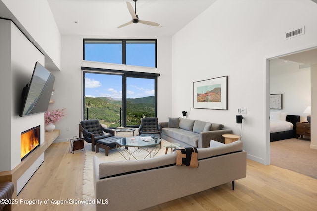 119 Wood Rd Unit 604, Snowmass Village, CO 81615 - living area with a towering ceiling, a glass covered fireplace, light wood-style floors, and ceiling fan