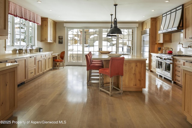 kitchen with premium appliances, custom range hood, a center island, light countertops, and light wood-type flooring