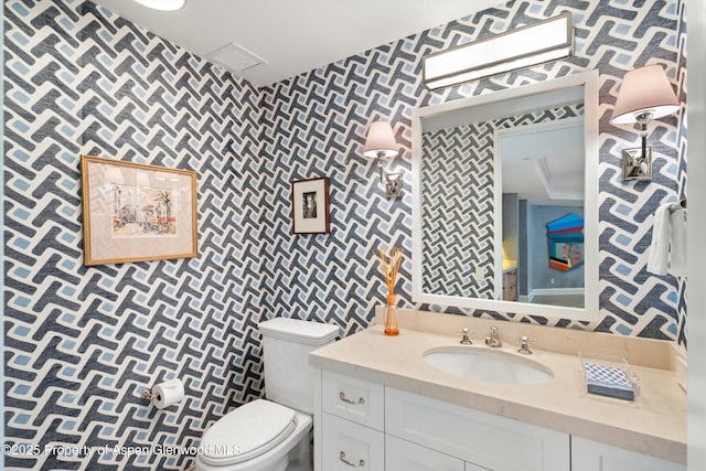 half bath with toilet, wallpapered walls, visible vents, and vanity