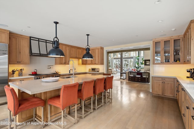 kitchen with light wood-style floors, glass insert cabinets, light countertops, and a sink