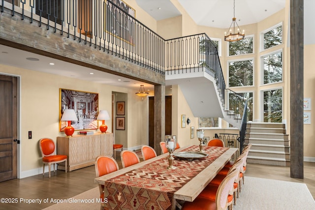 dining room featuring stairway, wood finished floors, a towering ceiling, and baseboards