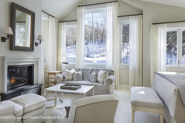 carpeted living room featuring vaulted ceiling and a glass covered fireplace