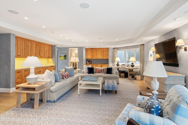 living area featuring light wood-style flooring, a tray ceiling, ornamental molding, and recessed lighting