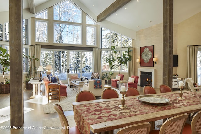 dining area featuring plenty of natural light, a fireplace, beamed ceiling, and a towering ceiling