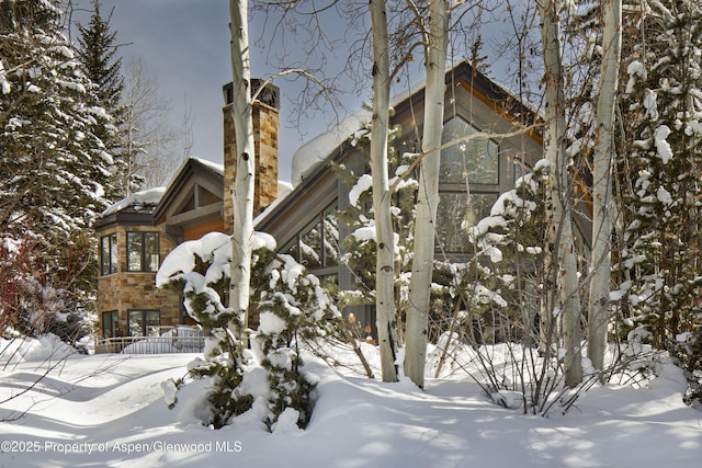 snow covered property with a sunroom and a chimney