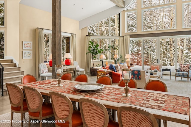 dining space featuring stairs, high vaulted ceiling, and beamed ceiling