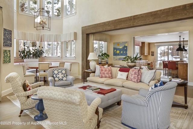 living room featuring an inviting chandelier, a high ceiling, and baseboards