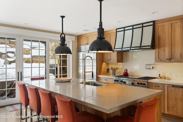 kitchen with a breakfast bar area, stove, a sink, an island with sink, and pendant lighting