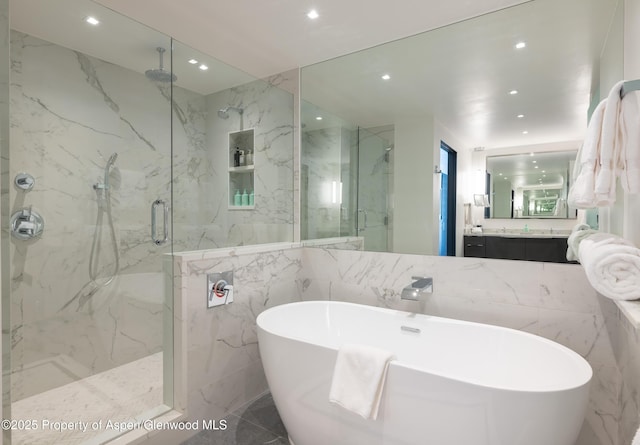 bathroom with plus walk in shower, tile walls, and vanity