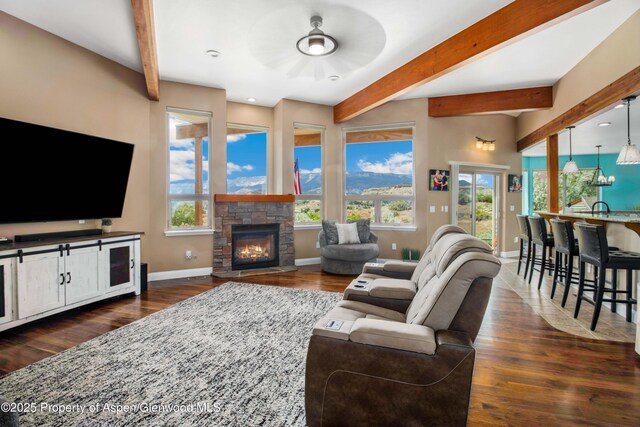 1783 Anvil View Ave, Rifle, CO 81650 - living room featuring a ceiling fan, beam ceiling, dark wood-style floors, plenty of natural light, and a stone fireplace