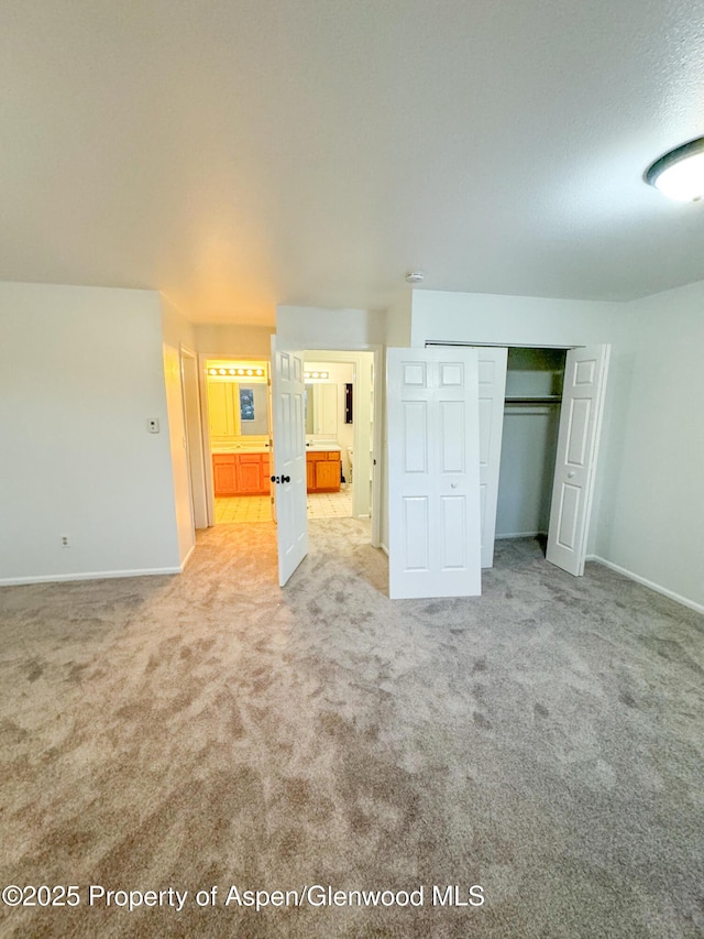 unfurnished bedroom with light colored carpet and a closet