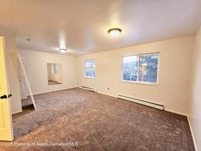 basement with dark carpet, a baseboard heating unit, and a textured ceiling