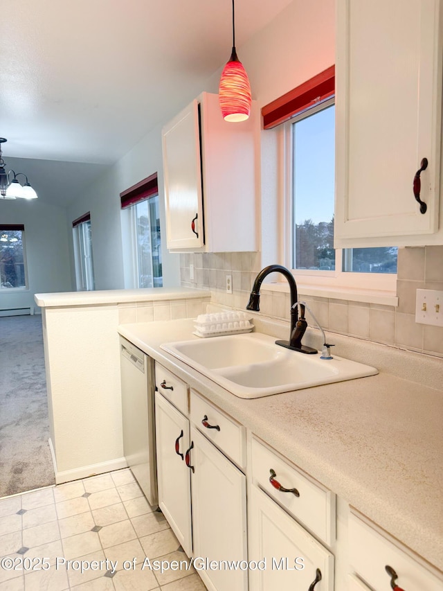 kitchen featuring tasteful backsplash, hanging light fixtures, stainless steel dishwasher, sink, and a healthy amount of sunlight