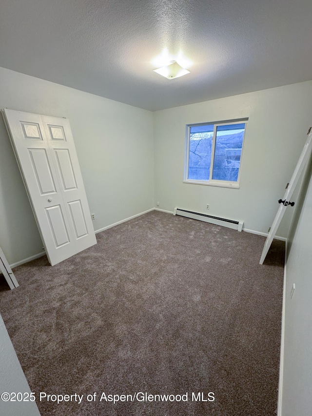 unfurnished bedroom with a baseboard radiator, a textured ceiling, and carpet