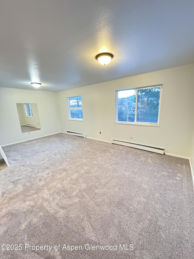 empty room with carpet floors, a textured ceiling, and a baseboard heating unit