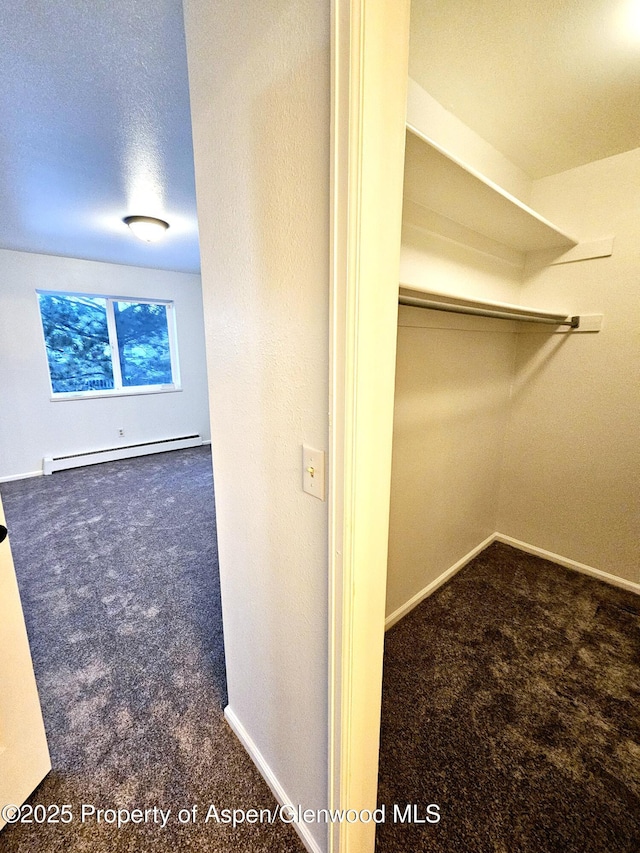 walk in closet with dark carpet and a baseboard radiator