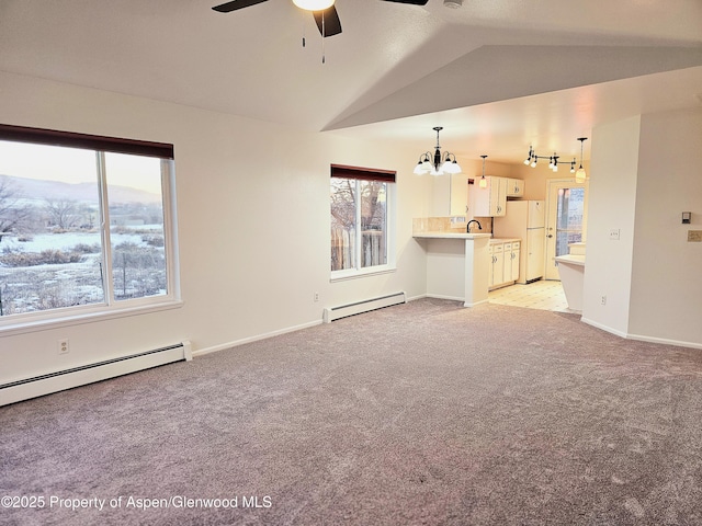 unfurnished living room with baseboard heating, lofted ceiling, sink, a mountain view, and light colored carpet