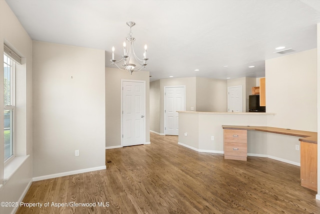 interior space with wood finished floors, black fridge, a chandelier, baseboards, and recessed lighting