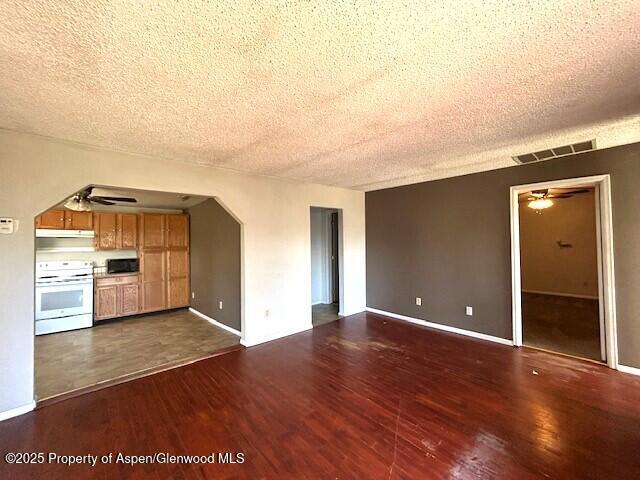 900 Breeze St, Craig, CO 81625 - unfurnished living room with a textured ceiling, dark wood finished floors, a ceiling fan, baseboards, and visible vents