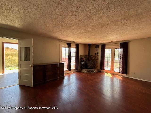900 Breeze St, Craig, CO 81625 - unfurnished living room featuring a textured ceiling, dark wood-style floors, baseboards, and a wood stove