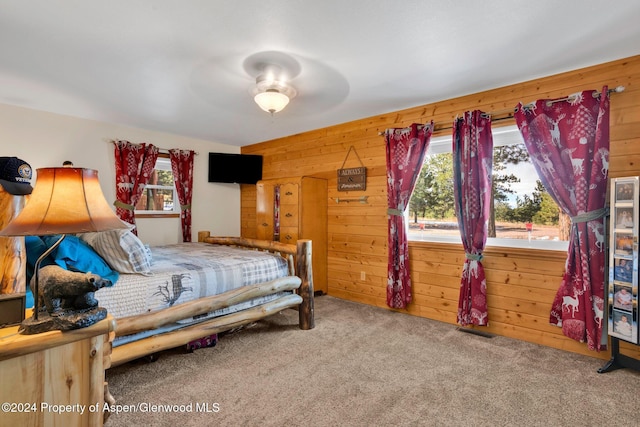 bedroom featuring carpet floors, ceiling fan, and wooden walls