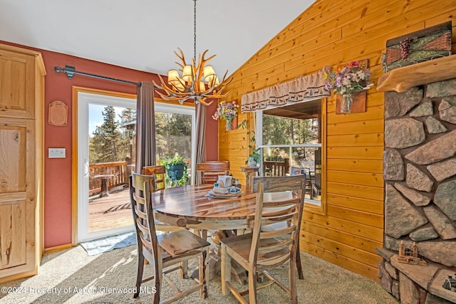 carpeted dining room featuring wood walls, vaulted ceiling, and a notable chandelier